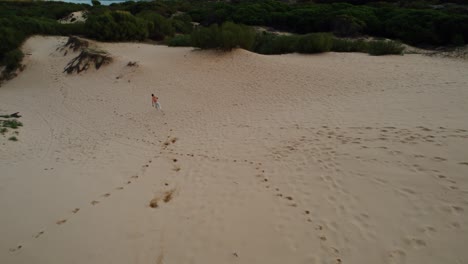 Drohnenaufnahme-Eines-Mannes,-Der-Durch-Spaniens-Sanddünen-Läuft,-Um-Zum-Strand-Zu-Gelangen