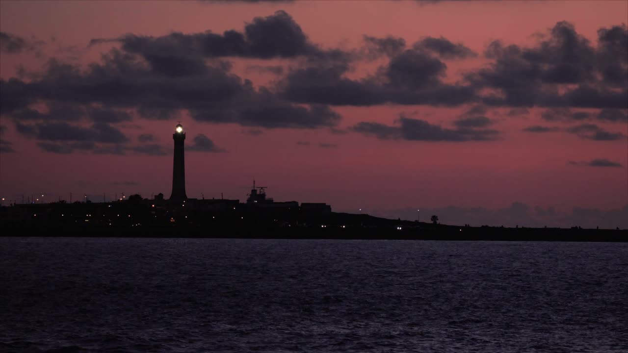 불빛이  ⁇ 은 일몰을 배경으로 빛나는 등대, 평화로운 바다 풍경과 지평선 위의 부드러운 빛