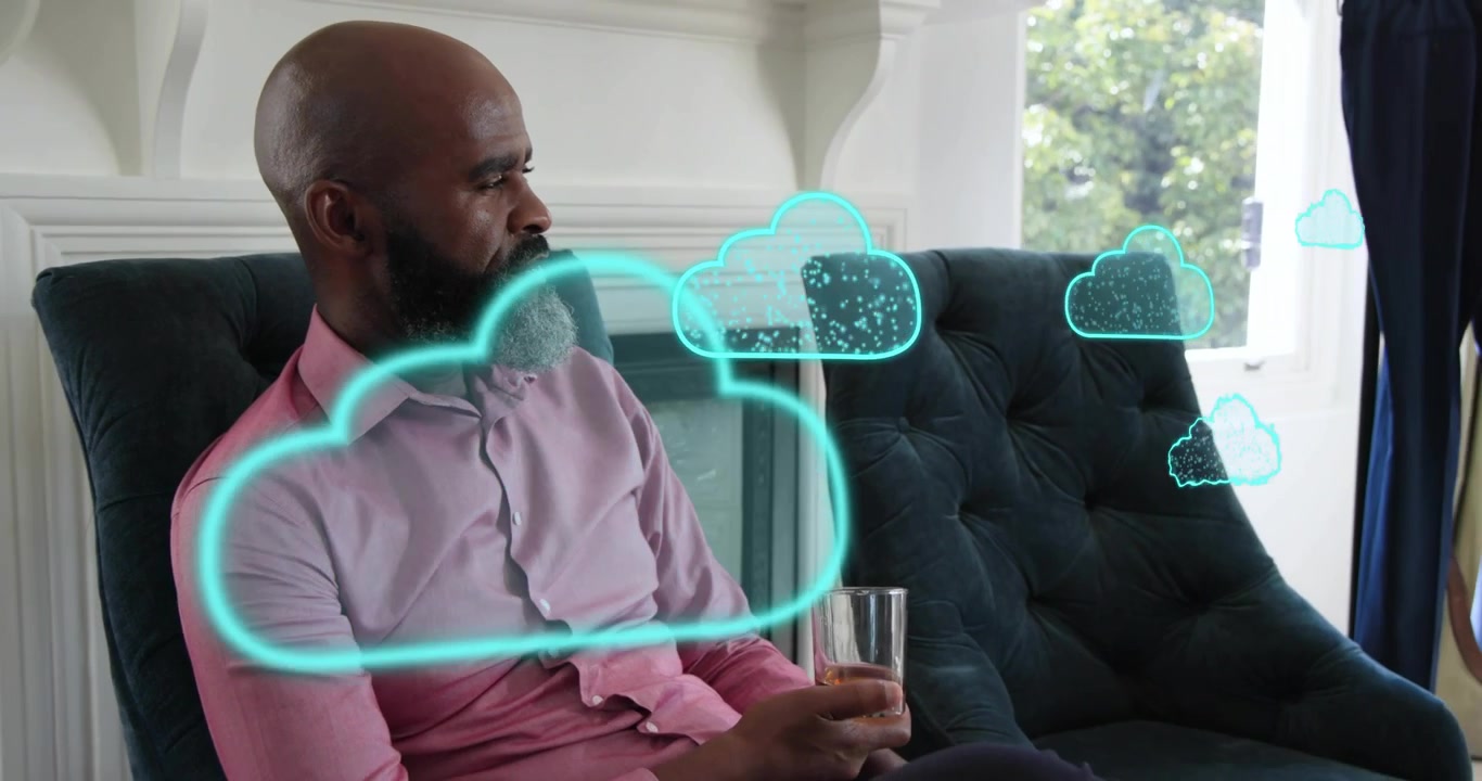Mature man sipping iced tea tracking cyan cloud icons appearing drifting toward window in tech demo