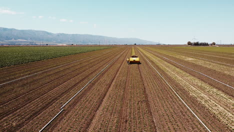 Dron-Amplio-En-Cámara-Lenta-Del-Campo-De-Cultivo-De-Alcachofas-Y-Máquina-De-Deshierbe-Avanzando