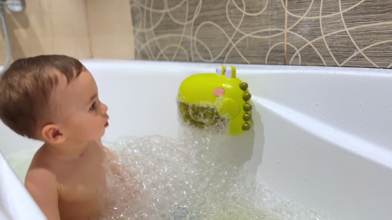 Toddler playing in a bath with a crocodile toy