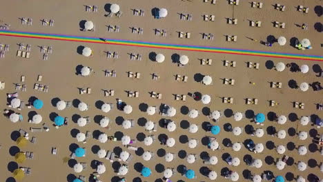 top down view of beach umbrellas and rainbow runway in tribute to lgbt movement in rimini, italy - aerial drone shot