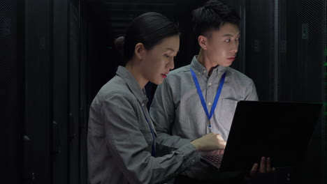 two smart engineers it technicians using laptop checking open rack server cabinet updating hardware cooperating in futuristic digital room of data center with rows of server racks super computers