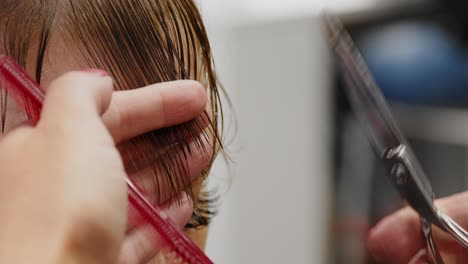 hair-stylist-combing-a-woman's-bangs-and-the-cutting-bangs-with-scissors