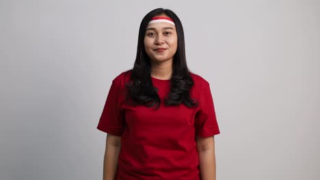 young asian woman giving salute to sideways and to the camera, celebrate indonesian independence day on 17 august