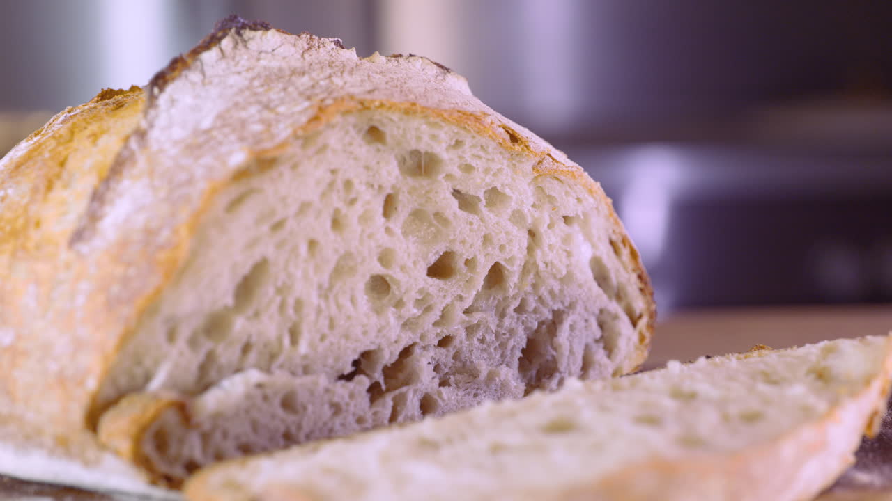 la mano mueve una rebanada de pan de masa fermentada en una tabla de madera - macro, pan shot