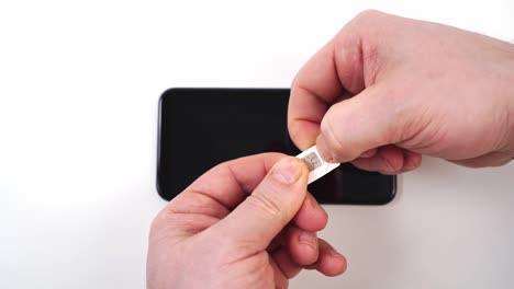 las manos de los hombres sacan una tarjeta nano sim de la tarjeta mini sim del adaptador.