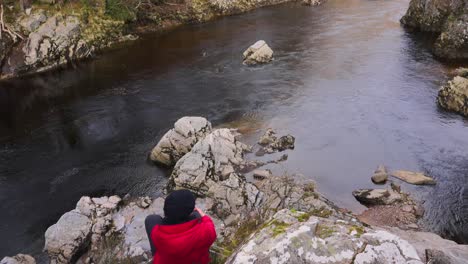 Slow-motion-shot-of-hiker-with-red-jacket-resting-enjoys-view-by-river