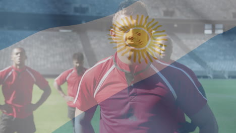 animation of argentinian flag waving over multi-ethnic male rugby team standing on a pitch