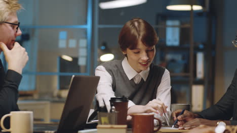 young businesswoman talking to diverse team at night office meeting