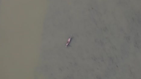 vista aérea de un pescador solitario en un barco de madera tradicional en el río