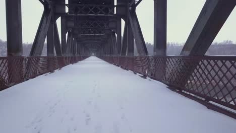 snowing winter pov along unused and abandoned steel truss bridge deck