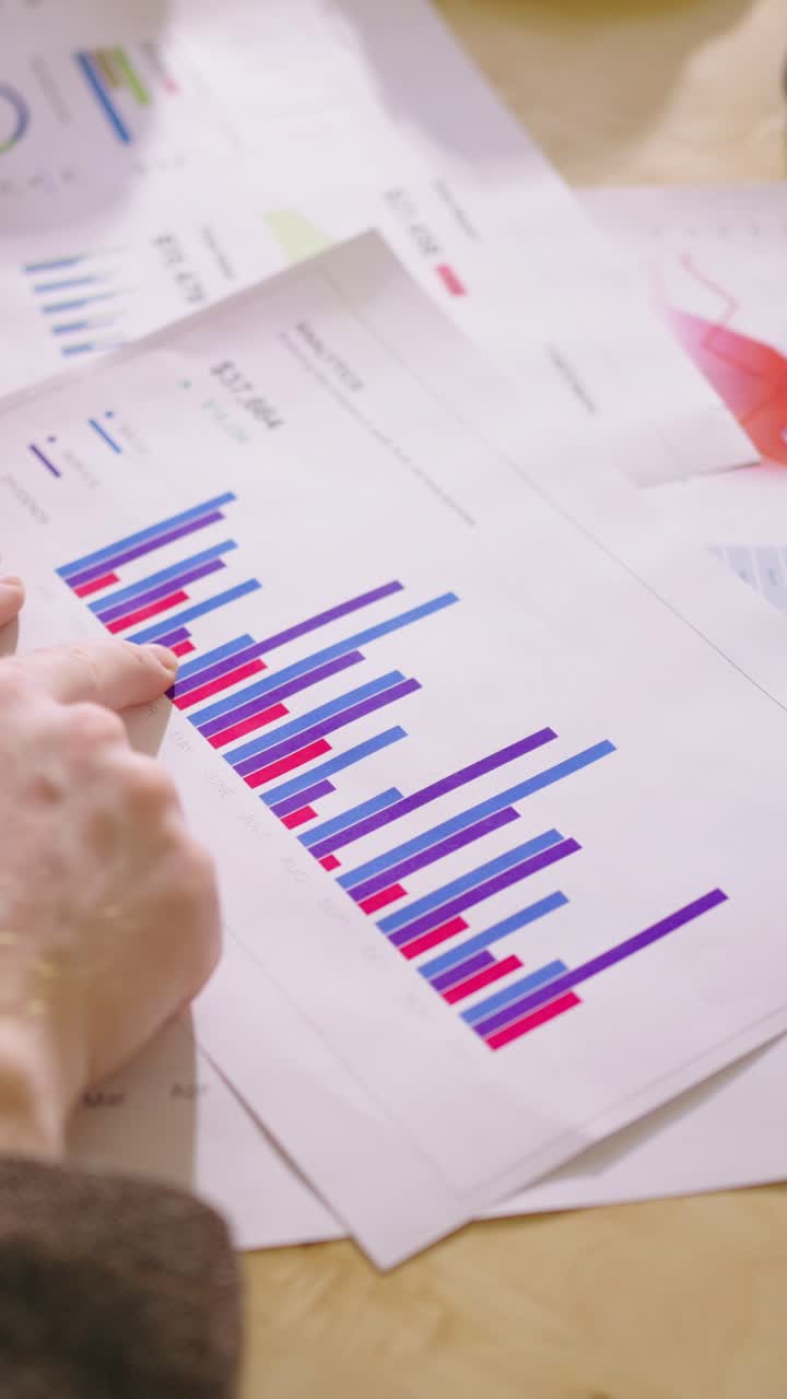 Nærbillede af hænder, der analyserer forretningsdiagrammer og finansielle data på papir