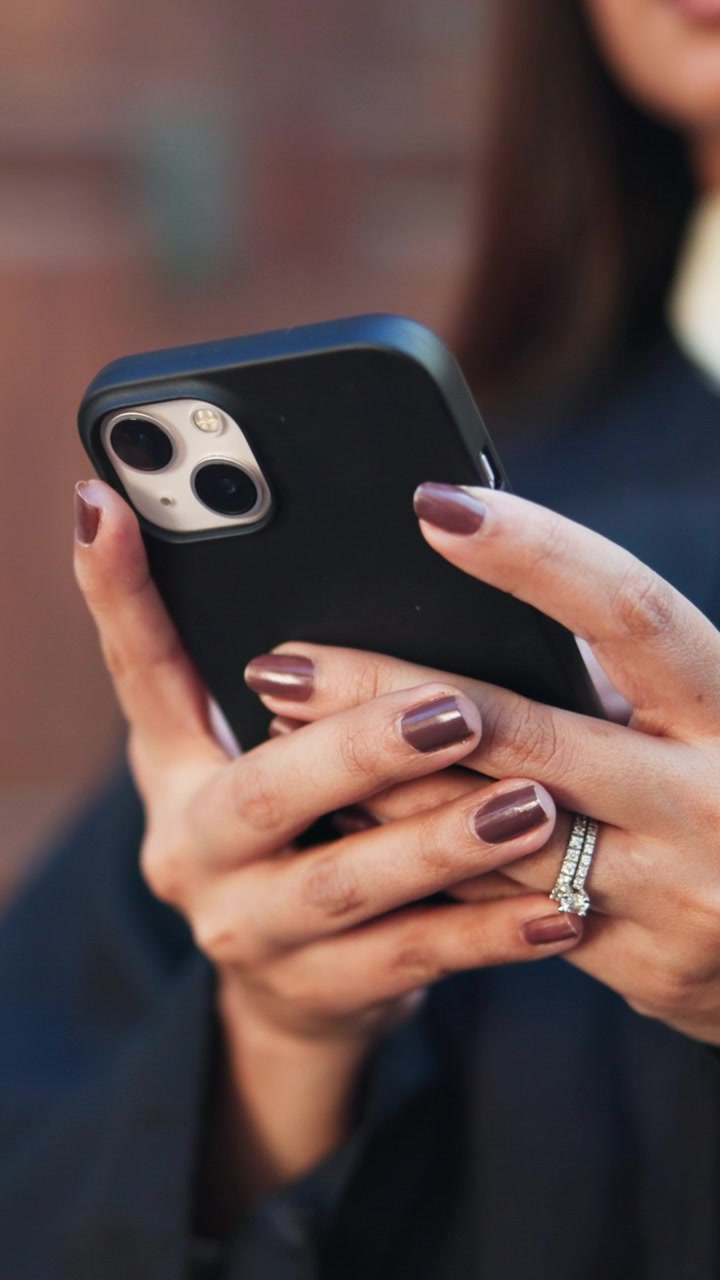 Donna che usa lo smartphone con unghie curate e anello con diamante