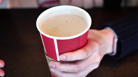 clip tomado en una cafetería de una mujer caucásica bebiendo una taza recargable con café o té caliente y hablando con las manos
