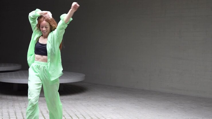 An energetic and cheerful woman dances outdoor in a fashionable green outfit with vibrant energy
