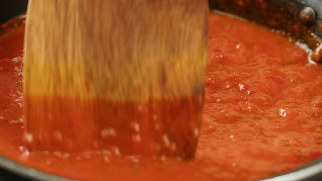 Chicken in tomato sauce is boiling on a frying pan with spices. Cooking tomato sauce curry with chicken fillet. Traditional Italian Mexican Asian dish. High quality studio shot for cafe, restaurant close up.