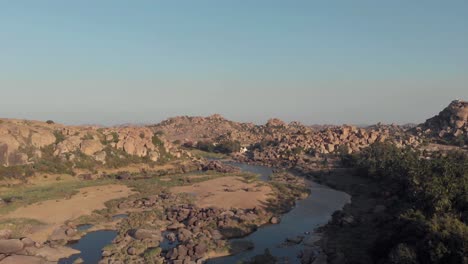 granite outcrops and rocky landscape alongside the tungabhadra river in hampi, karnataka, india - aerial ascending wide shot