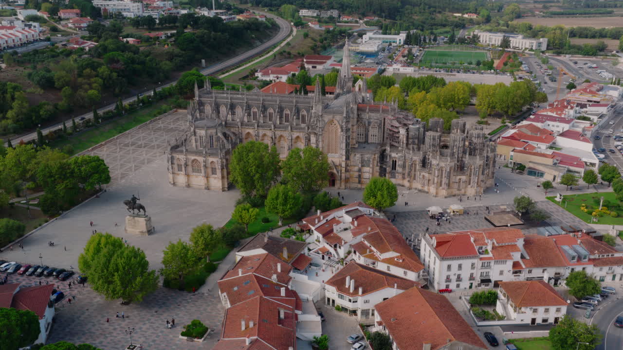 Mosteiro da Batalha aerial pull‑back, wide reveal from monastery to surrounding town and countryside