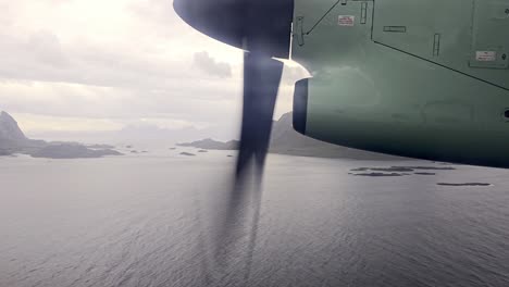 window view from wideroe propeller airplane cruising at low altitude over sea beside lofoten mountains