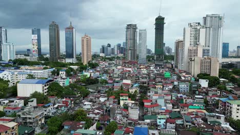 Rising-aerial-shot-of-dense-neighborhood-in-Manila,-Philippines-near-high-rises