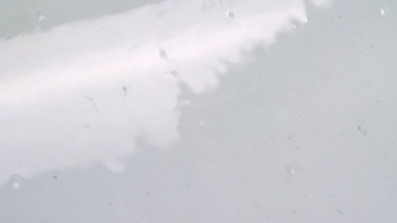 вода с пузырьками, стекающая по гладкой и глянцевой стене