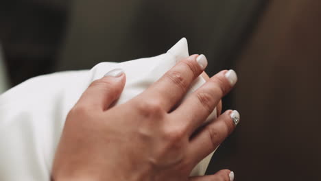 woman in white clothes with manicure taps hand on knee