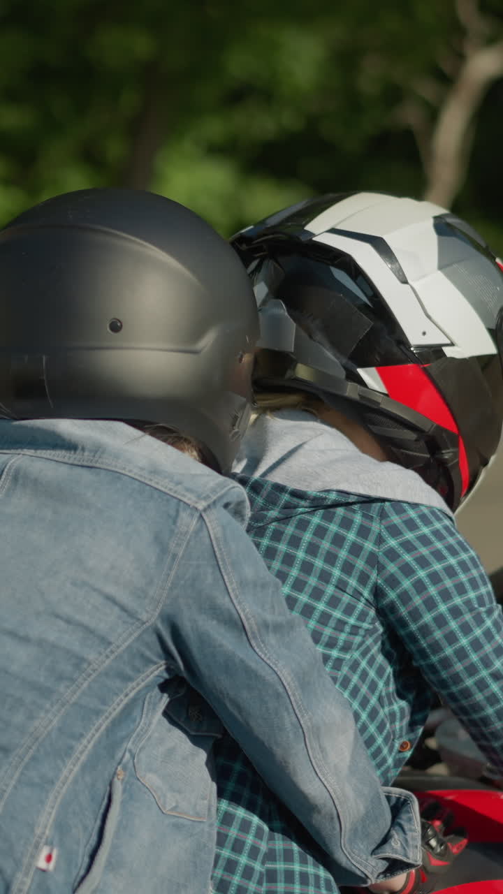 Two ladies riding a power bike on a tarred road, wearing helmets, while a jeep passes them on the side, the background includes a blur of grass by the roadside