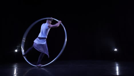 un acróbata muscular muestra trucos difíciles para el equilibrio y la concentración mientras gira en una rueda de cir