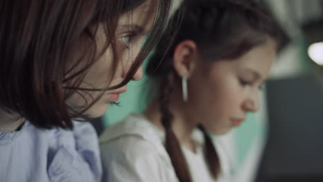 Two-serious-schoolgirls-sitting-together-looking-down-closeup.-Study-concept.