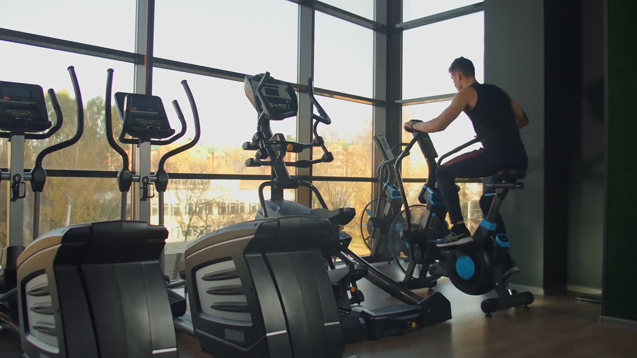 Young active men spinning a air bike in gym with trainers. male training on air bike.