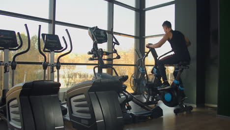 young active men spinning a air bike in gym with trainers. male training on air bike.