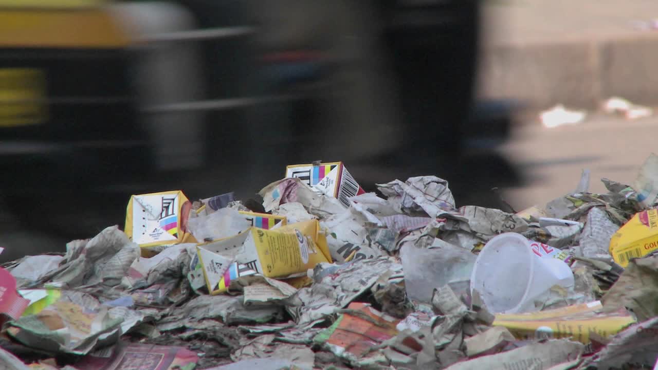 vista cercana de un montón de basura al lado de una calle muy transitada