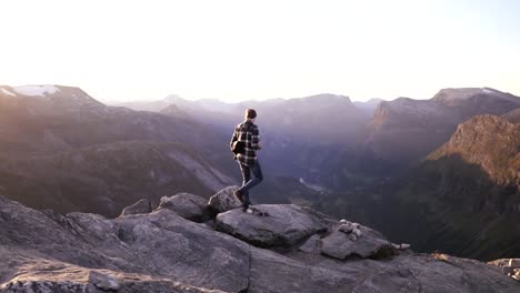 Man-walking-at-the-peak-of-a-mountain-at-sunset-in-slow-motion,-Norway,-Europe