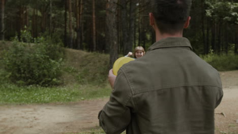 father and son playing frisbee in the forest