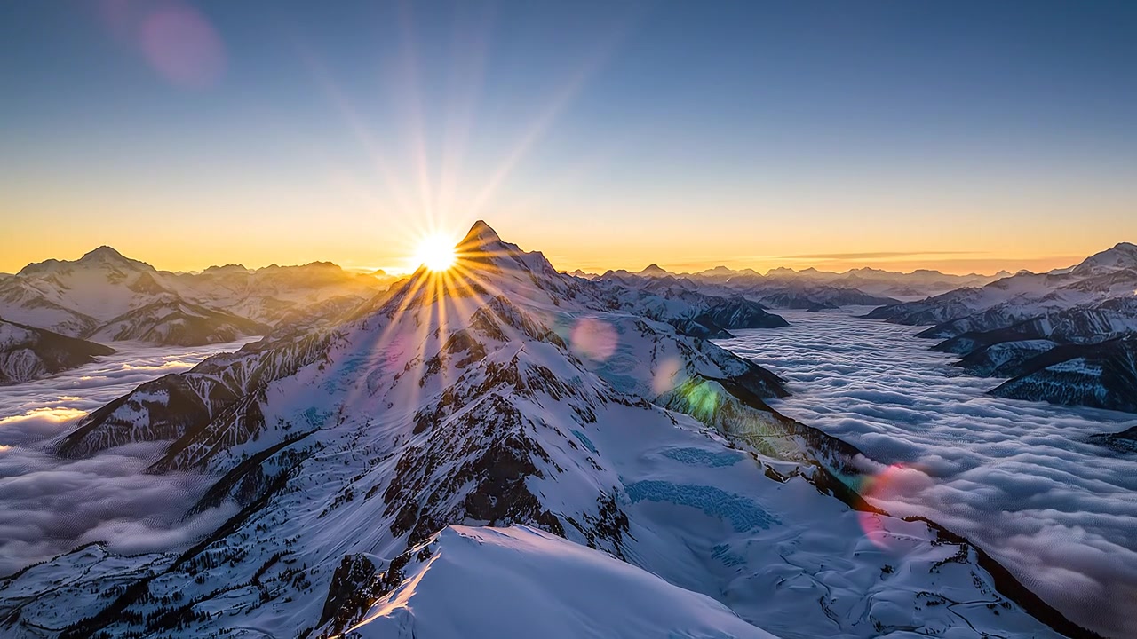 Amanecer dorado sobre picos de montañas cubiertos de nieve y un mar de nubes.
