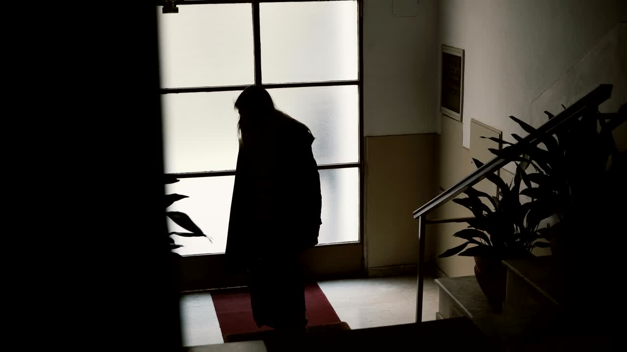 젊은 사업가 여성이 가방과 함께 아파트에 들어갑니다. 여성은 문을 열고 계단으로 올라갑니다.