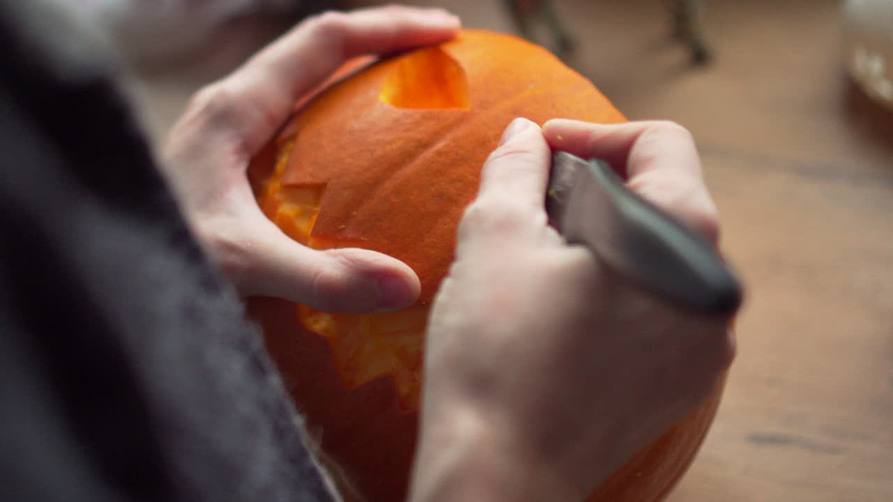 imágenes de una persona tallando los dientes de una calabaza de halloween