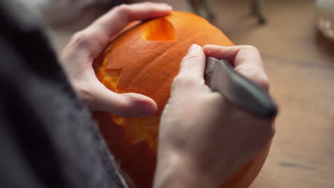 footage of a person carving out the teeth of a halloween pumpkin