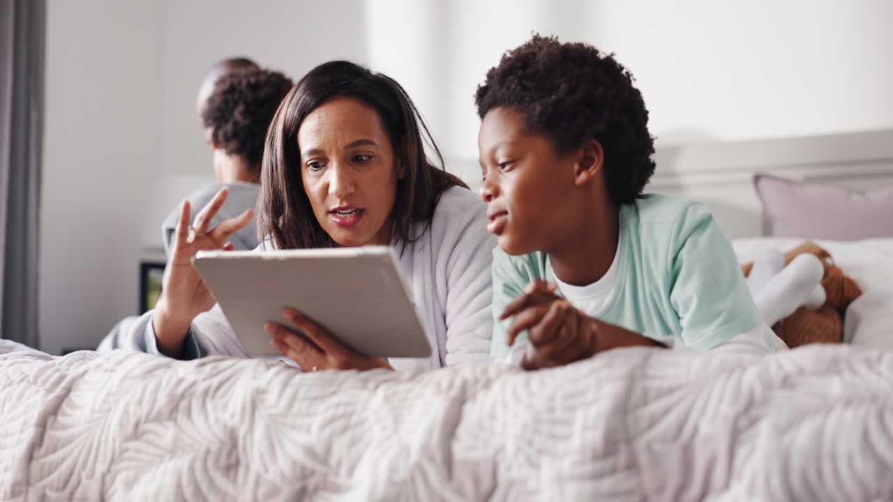 Mother and Son Enjoying Tablet on Bed