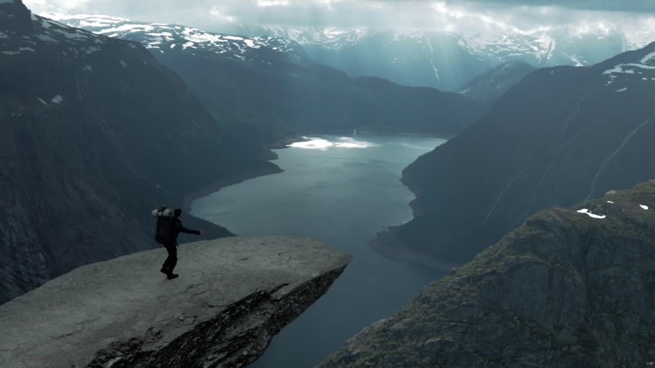 Brave man walking on Trolltunga with majestic view, handheld view
