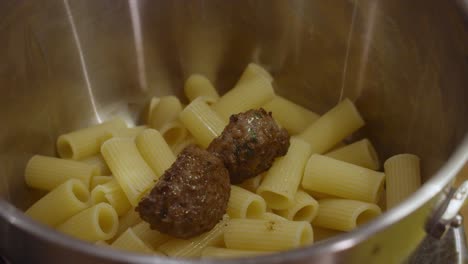 Adding-meat-balls-to-pasta-inside-metal-cooking-pot