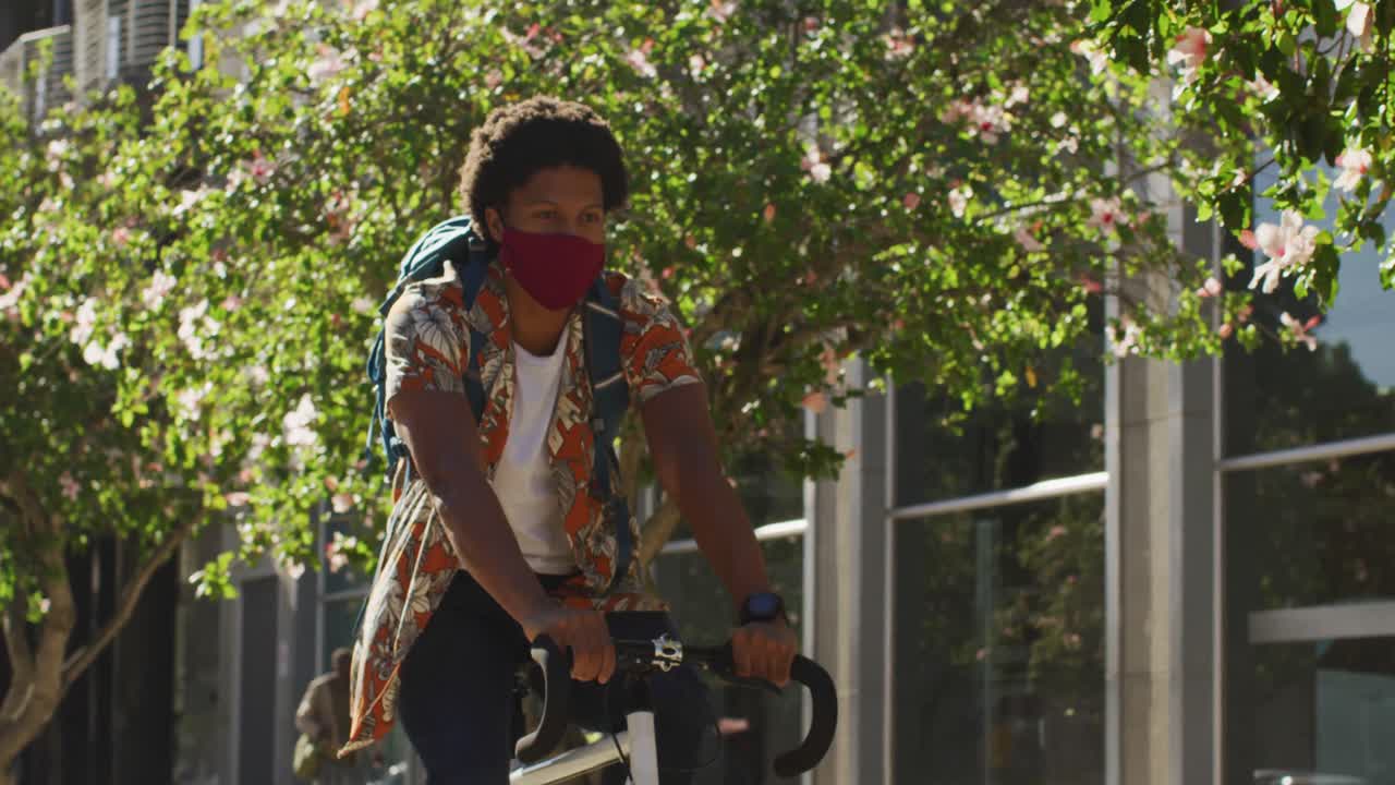 거리에서 자전거를 타고 마스크를 쓴 도시에 있는 아프리카계 미국인