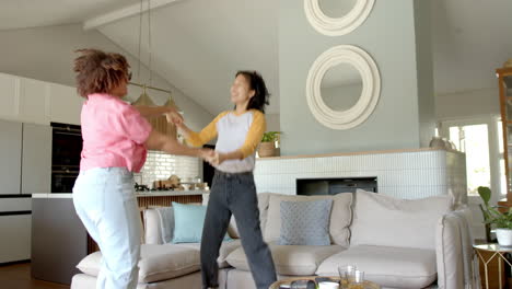 dancing and laughing, two diverse women friends enjoying time together in living room