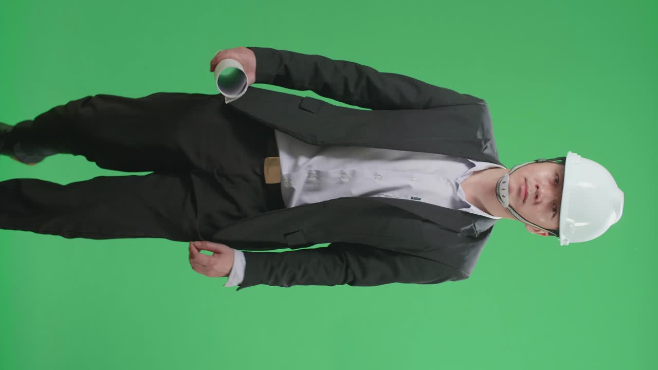 Asian Chief Engineer In The Hard Hat Holding Blueprint And Walks On Green Screen Chroma Key