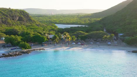 slow aerial pan across turquoise blue water and palm trees of daaibooi beach curacao