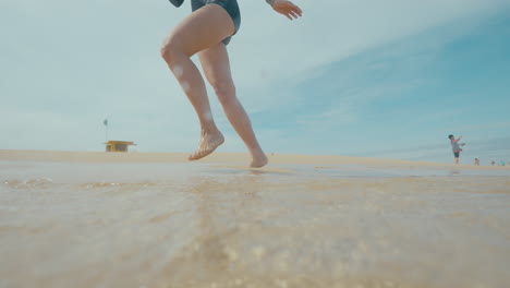 person walking through shallow water on a beach