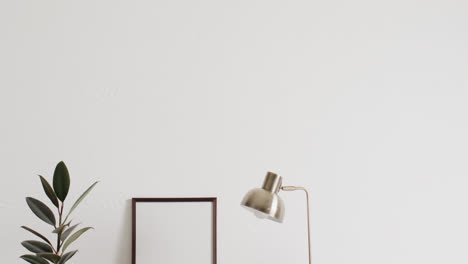 Wooden-frame-with-copy-space-on-white-background-with-plants-on-desk-against-white-wall