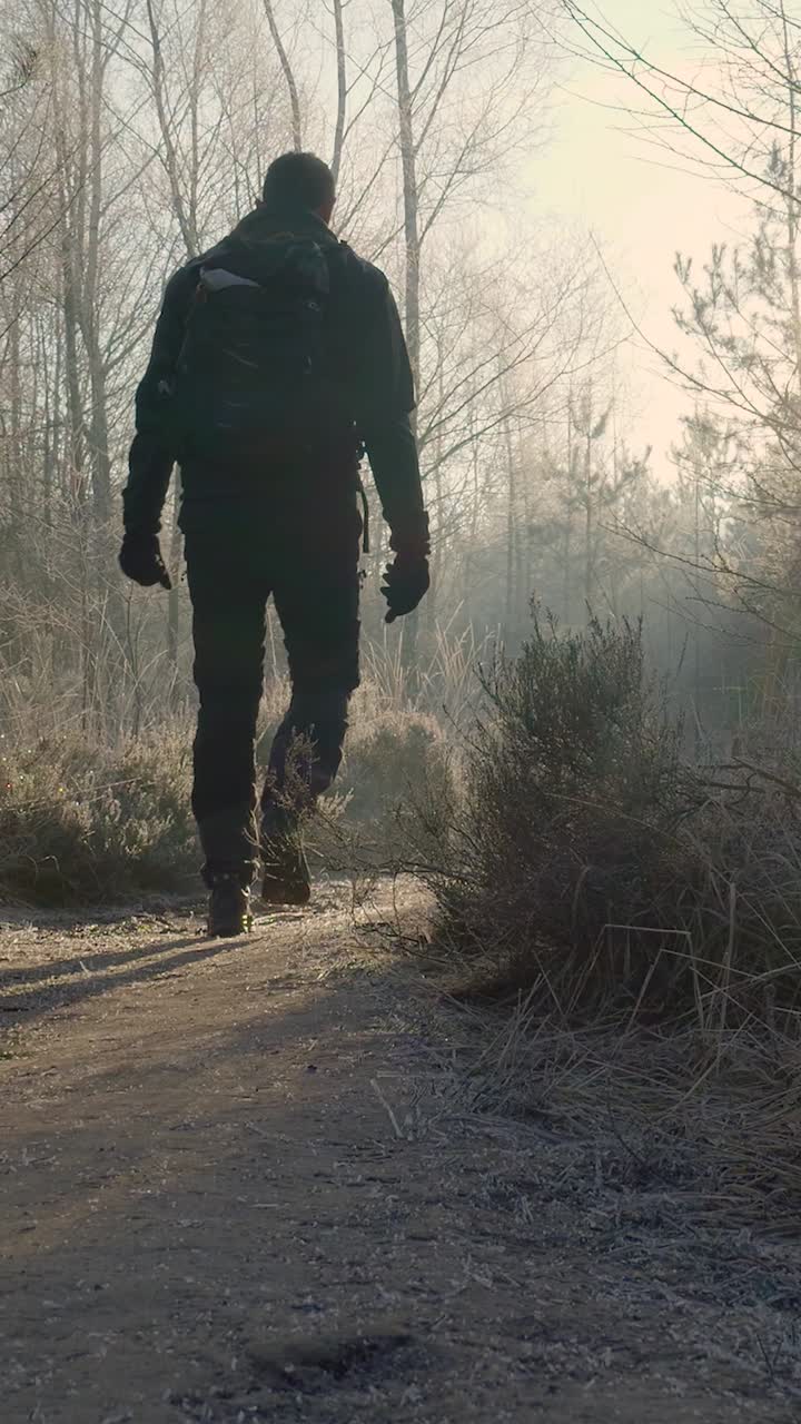 hombre caminando en un bosque de invierno al amanecer