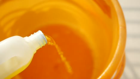 pouring liquid detergent into a bucket